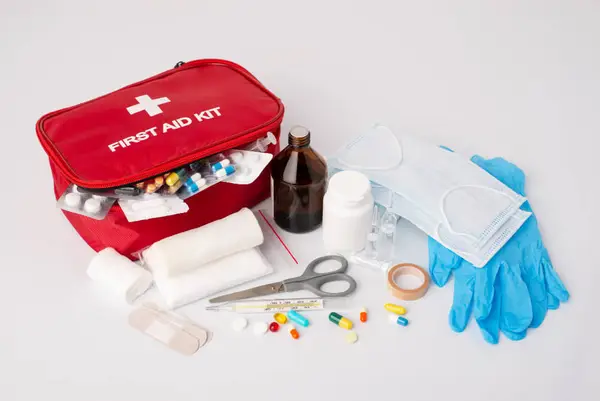 A red first aid kit with supplies like bandages, gloves, and medicine bottles, highlighting the essentials for emergency medical care.